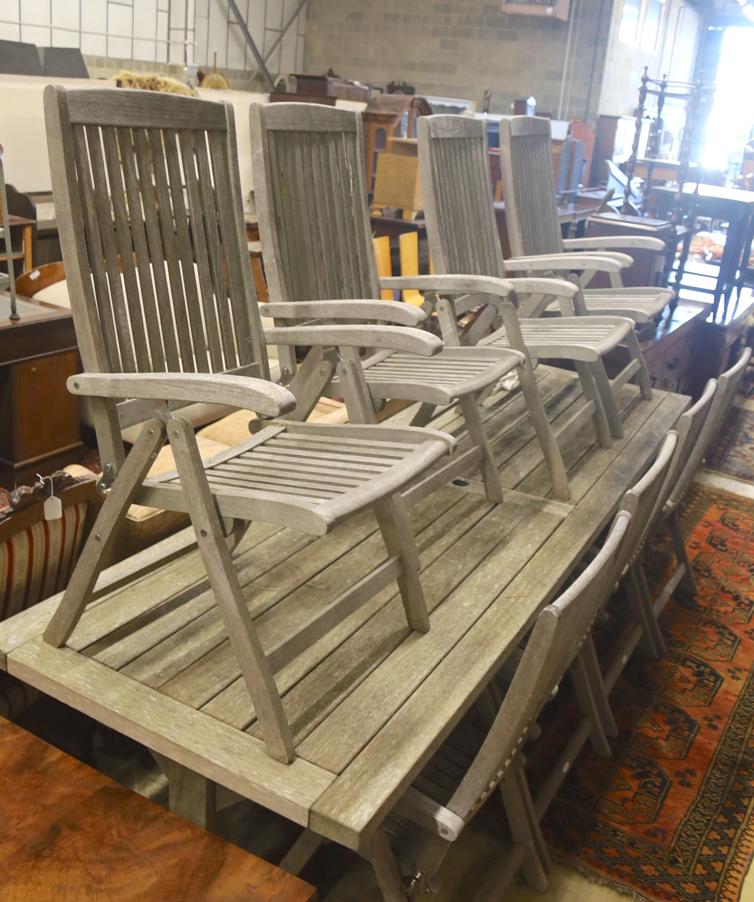 A suite of furniture comprising a weathered teak garden table, length 290cm, depth 90cm, height 74cm, and a set of eight Neptune teak folding garden armchairs